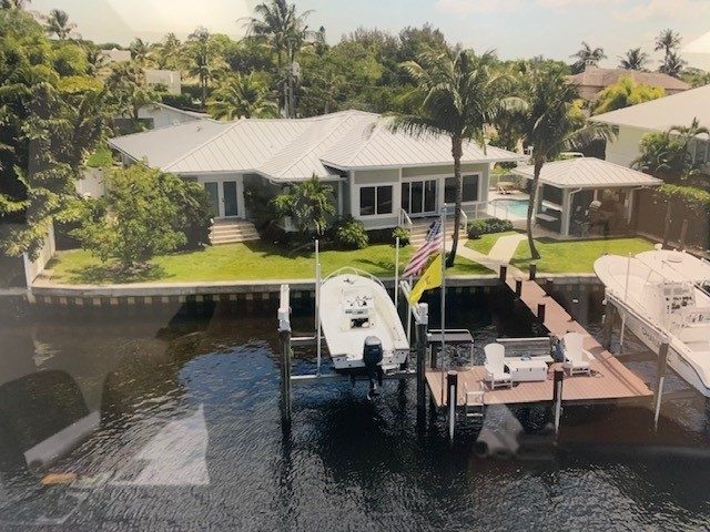 The same house from upriver, flag flying at the dock