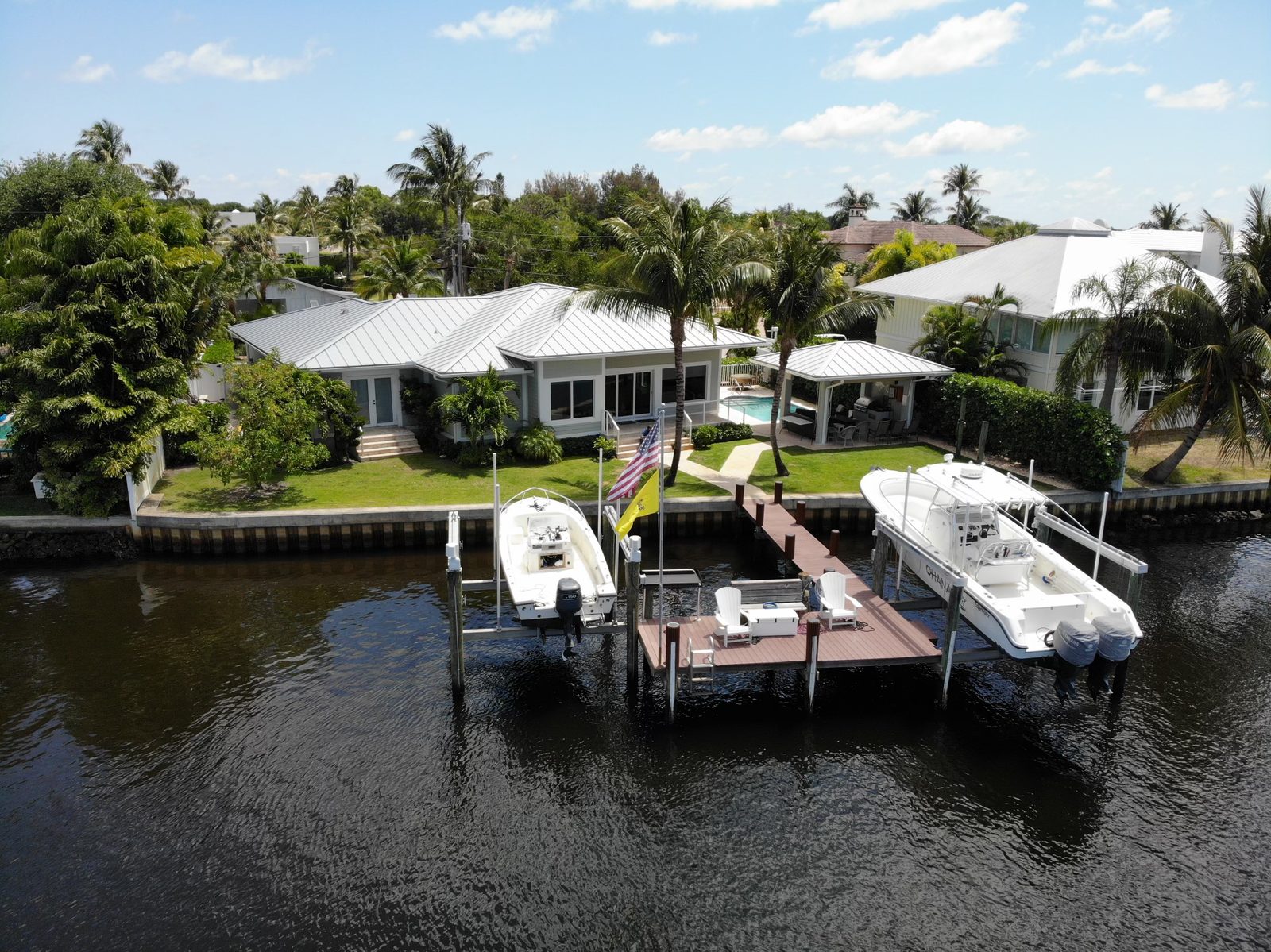 Aerial view of a waterfront home with a dock, two boat lifts and a pool