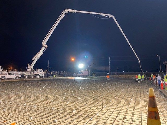 Night concrete pour on a canopy deck with a pump truck boom overhead