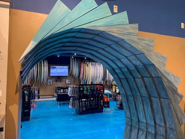 Surf shop interior with a sculpted wave archway over the board racks