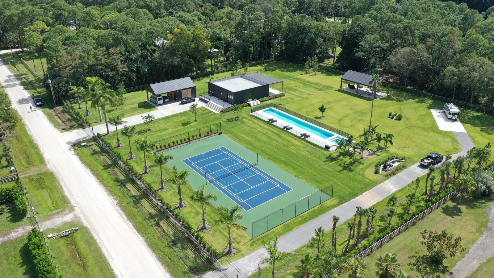Aerial view of a large estate with a tennis court, pool and guest buildings