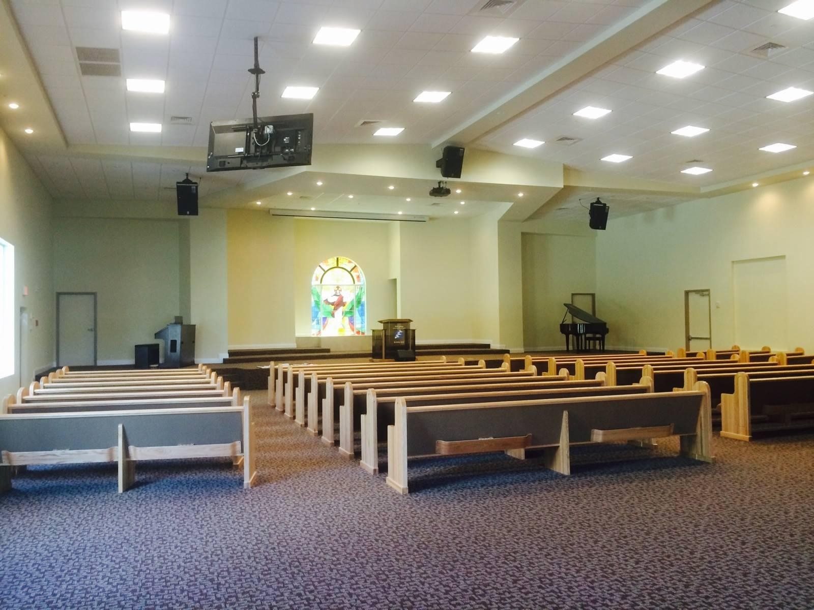 Church sanctuary with wooden pews and a stained glass window