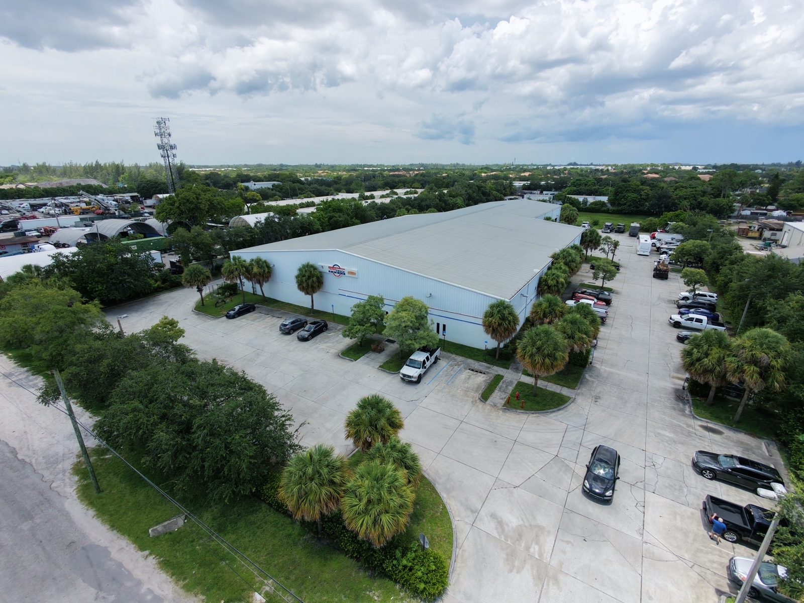 Aerial view of a blue-roofed warehouse and parts building with parking