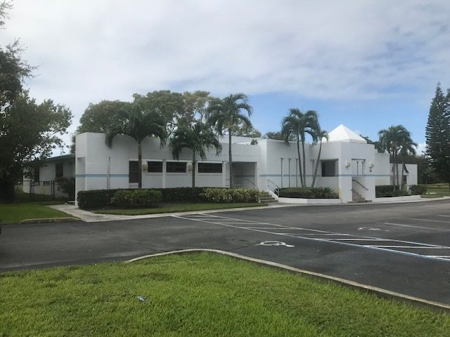 White modern church building with palm trees and a pitched entry