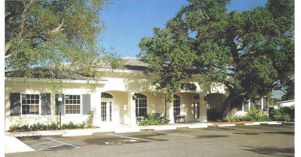 Single-story office building with dormer windows under mature oaks at Village Square Professional Park