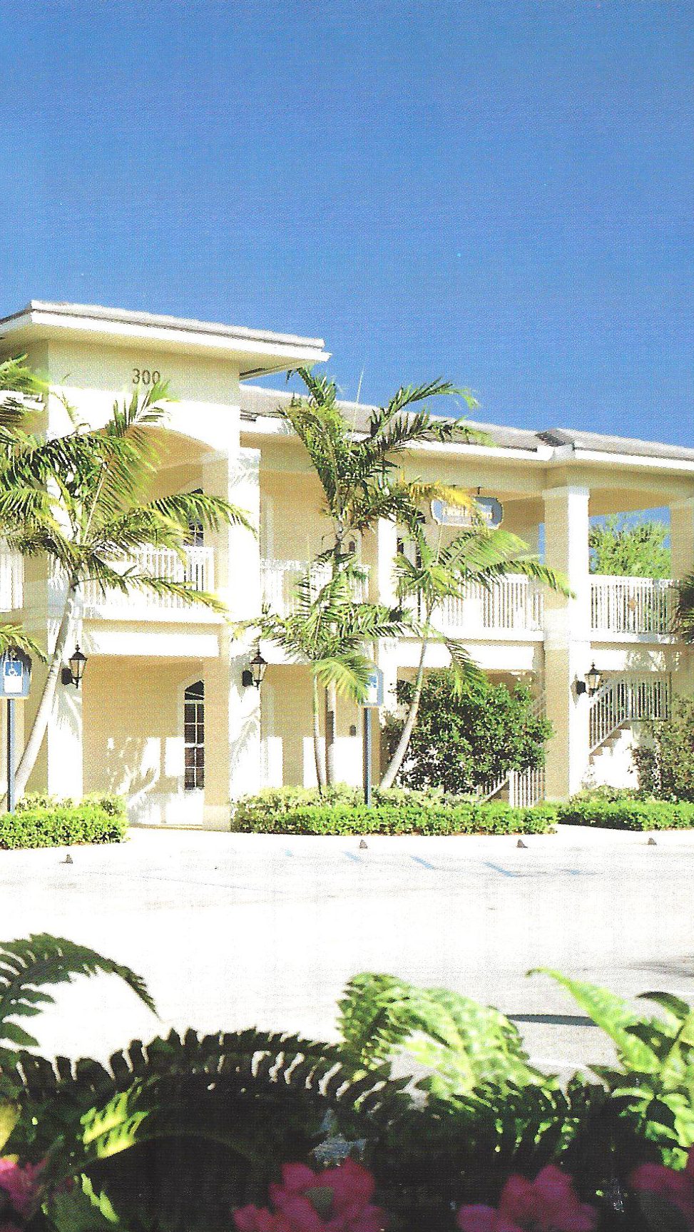 Two-story office building with white railings and palm trees at Village Square Professional Park